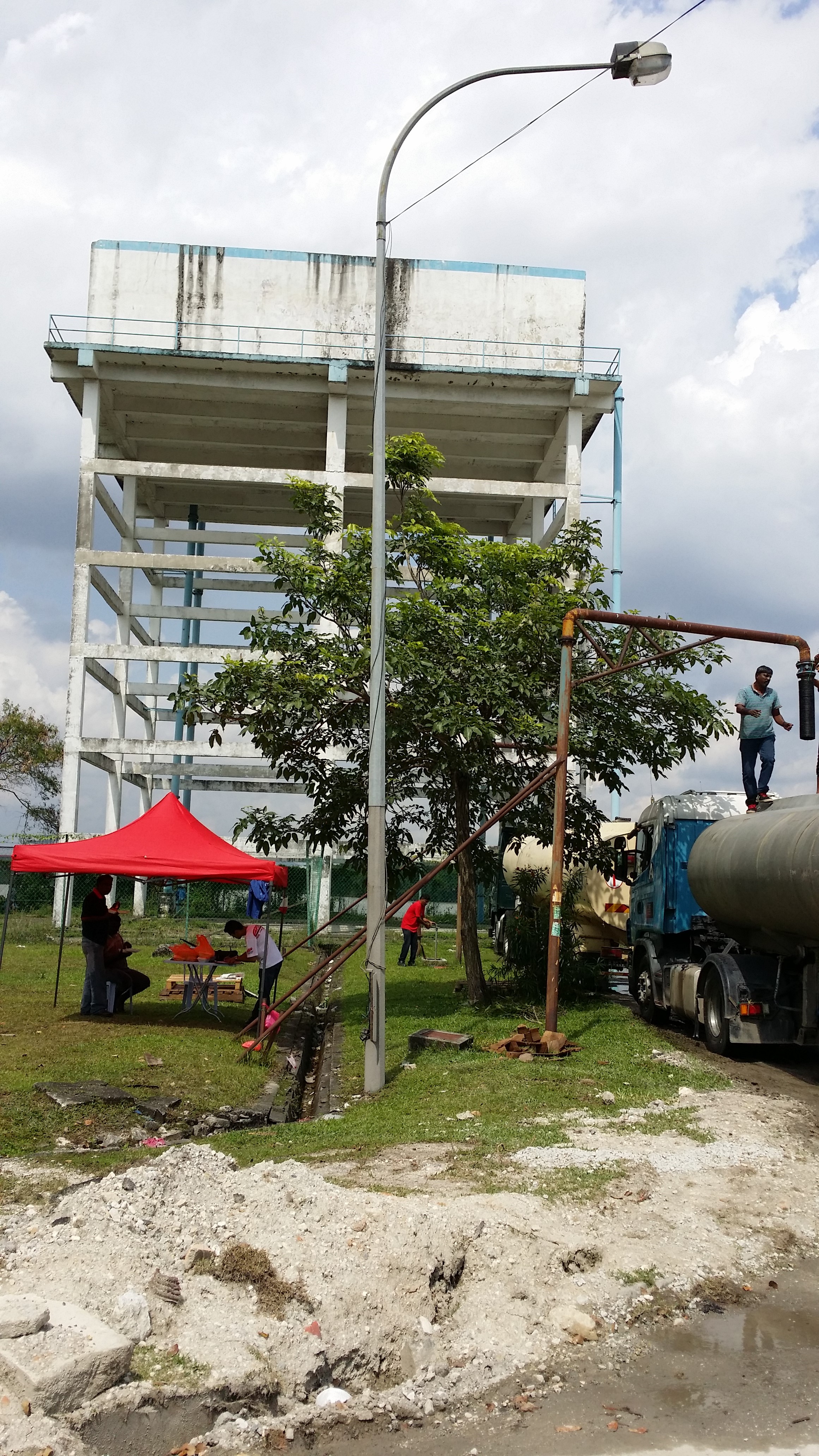 Water tanker loading beside a water storage tower